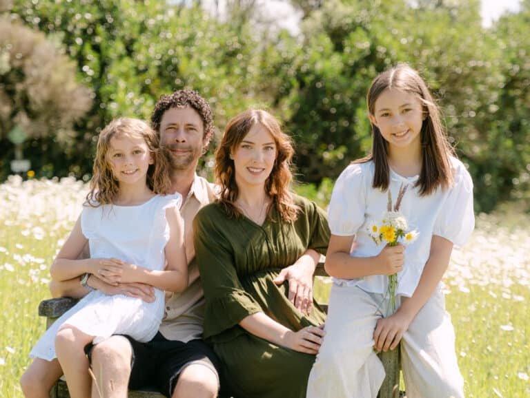 Whole family on bench looking at camera during maternity session in Hamilton