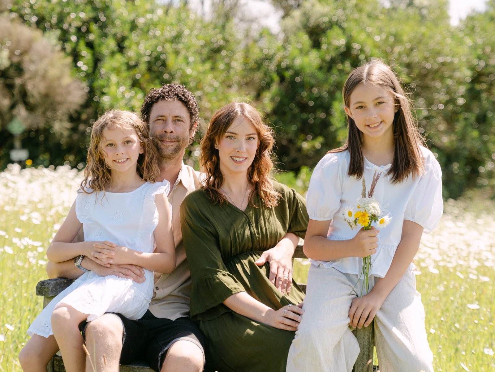 Whole family on bench looking at camera during maternity session in Hamilton
