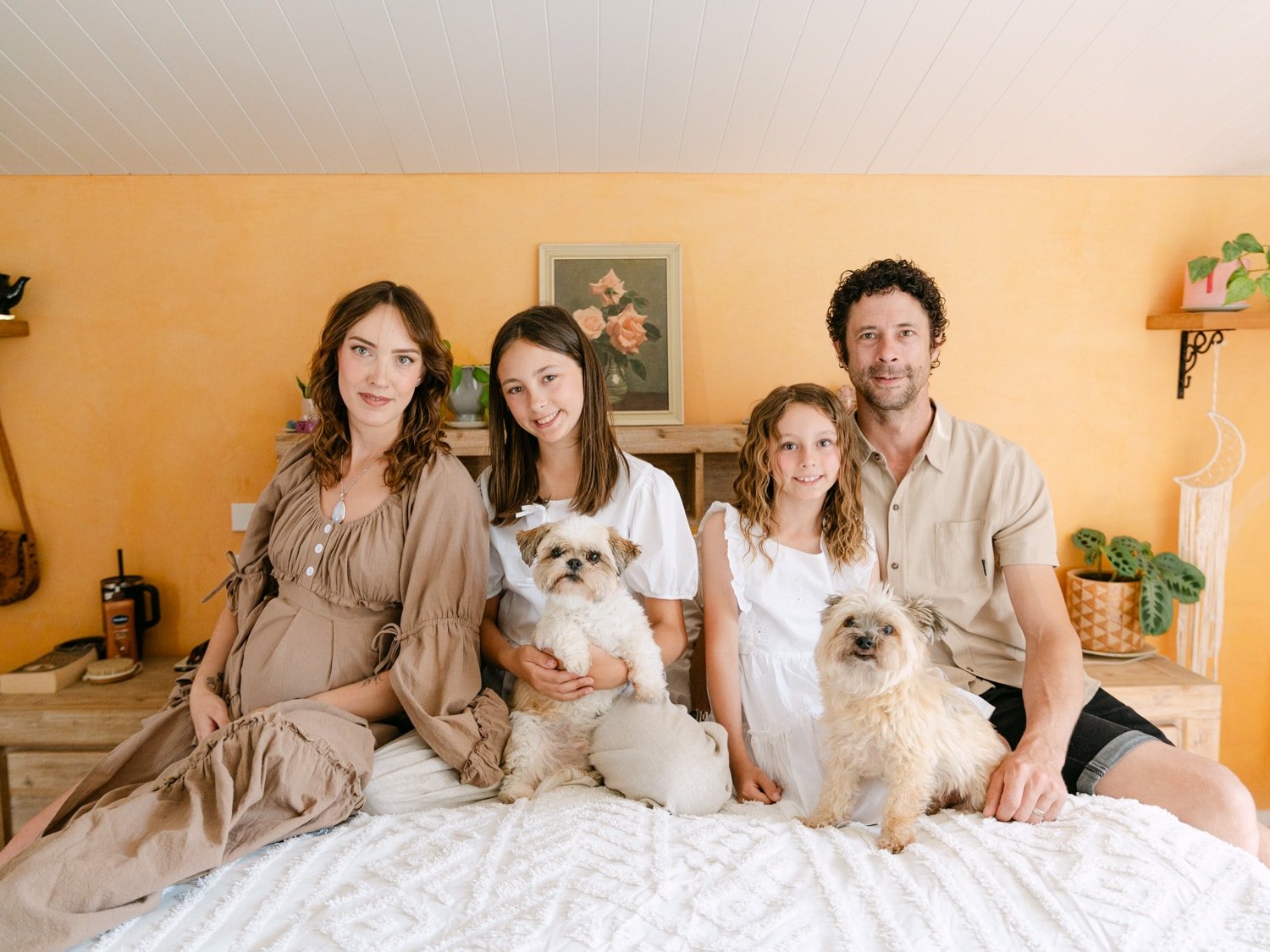 whole family and dogs sitting on parents bed posing for photo during maternity session in Hamilton