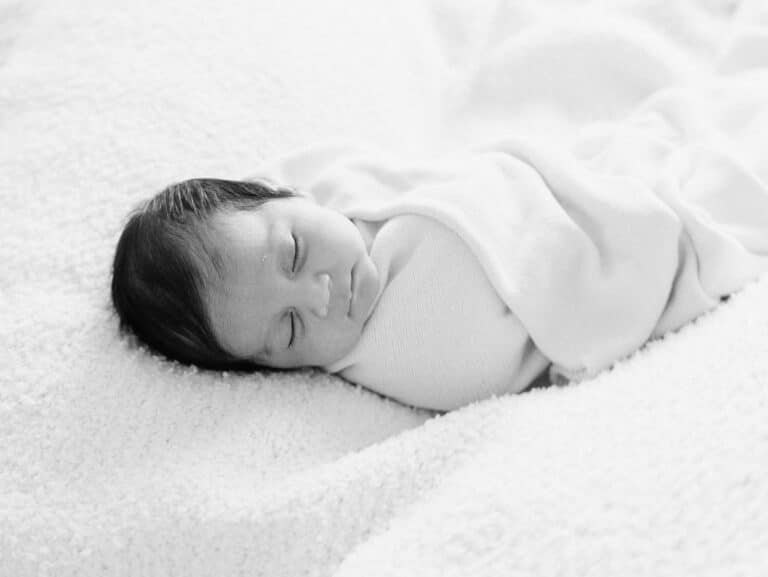 baby wrapped and asleep on a blanket during a newborn session at home in Hamilton