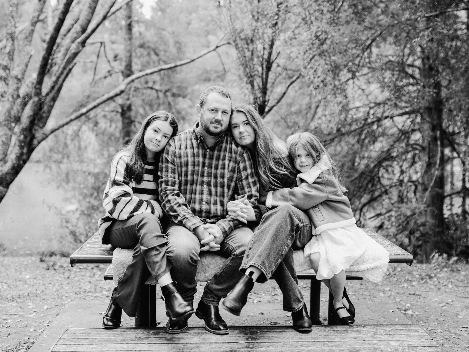 Katie and her family sitting on a bench and posing for a photo during a family session at McLaren Falls Park