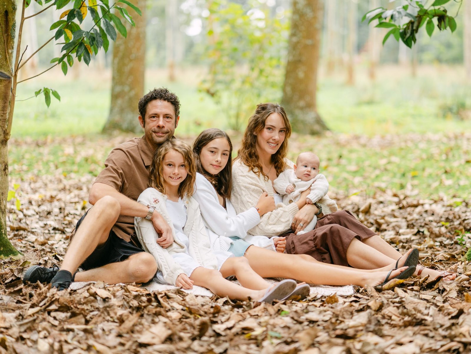 posing on blanket for a whole family photo during a family session at taitua Arboretum