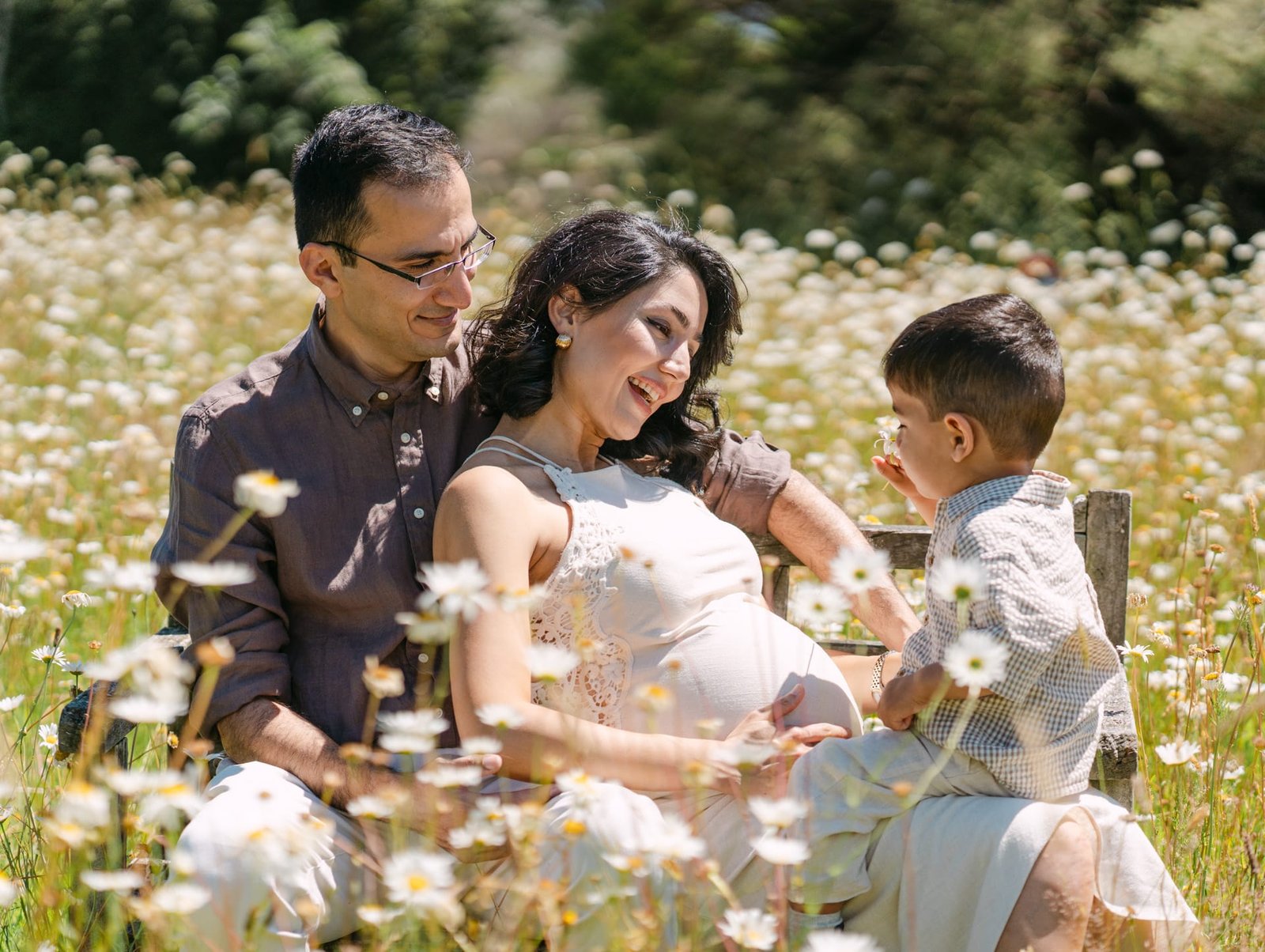 Tina and Pouya looking at little Neil and smiling during a maternity session at Hamilton in a park.