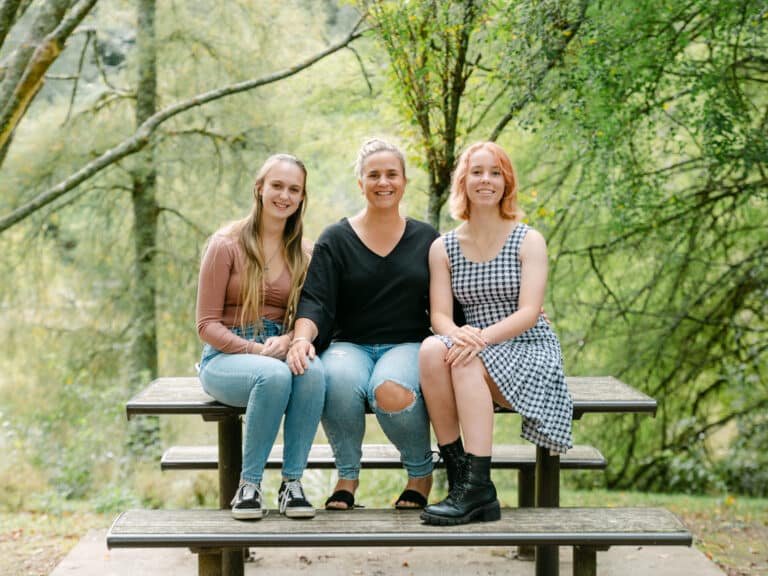 Rachel and her two daughters sitting on a bench and posing for camera during a family shoot at McLaren Falls Park
